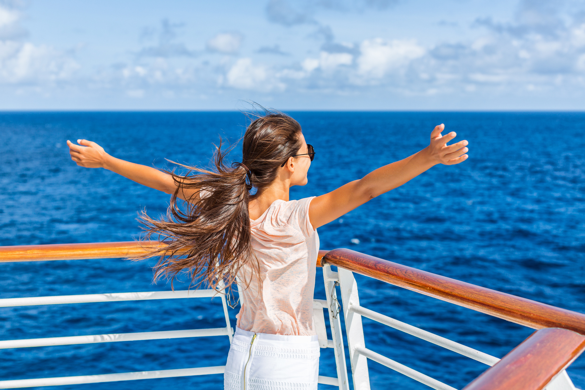 Cruise ship vacation woman enjoying travel vacation having fun at sea. Free carefree happy girl looking at ocean with open arms in freedom pose.